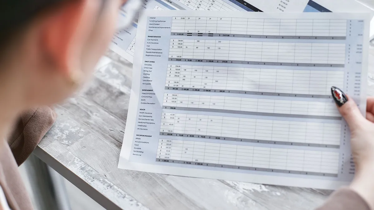 Calculator and monthly budget sheet used to plan consumer proposal loans on a kitchen table