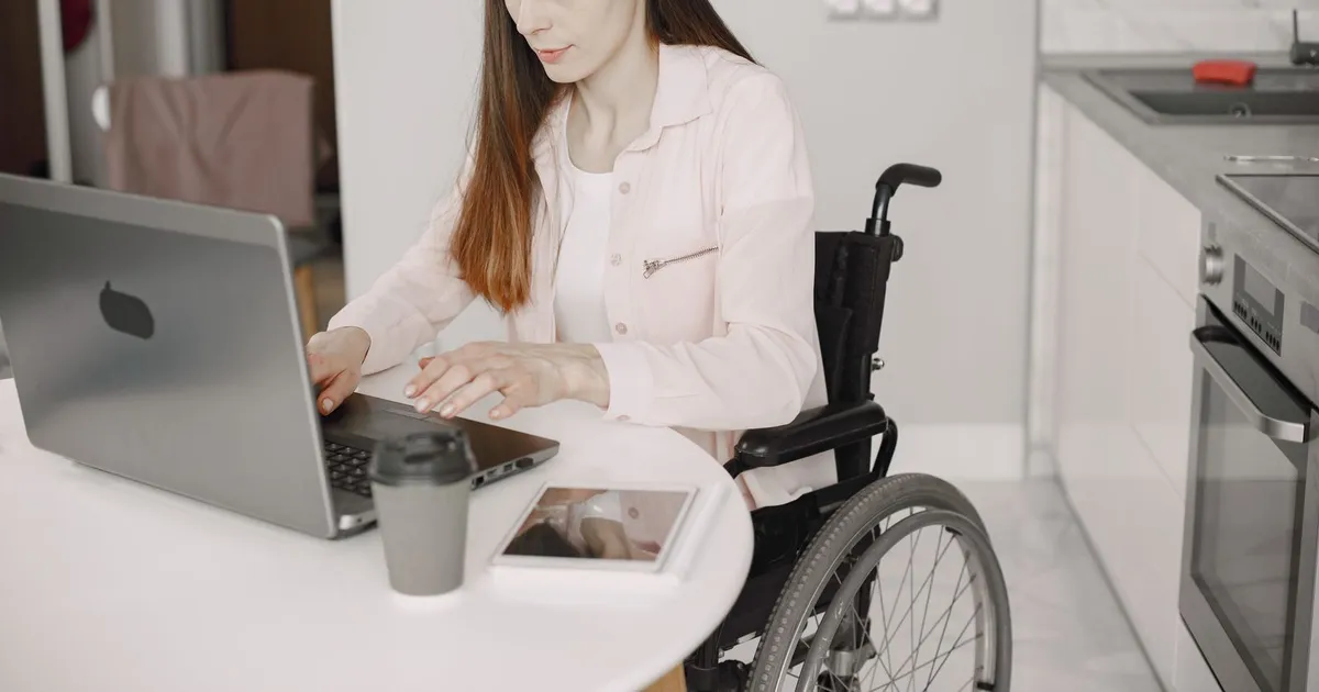 Person with a disability comparing disability loans offers on a laptop in their kitchen