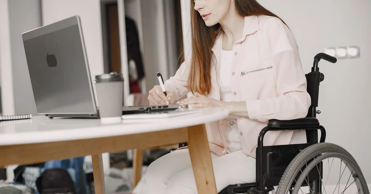 Person in a wheelchair applying for ODSP loans on a laptop at home