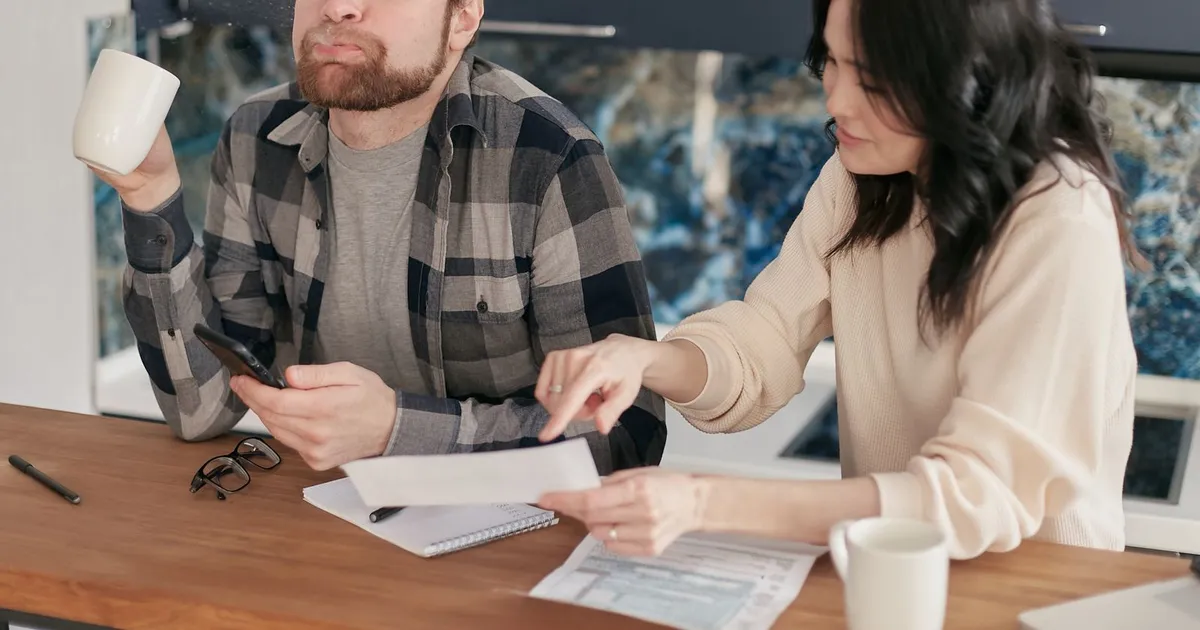 Stressed Canadian borrower sorting bills at a kitchen table after a payday loan rollover