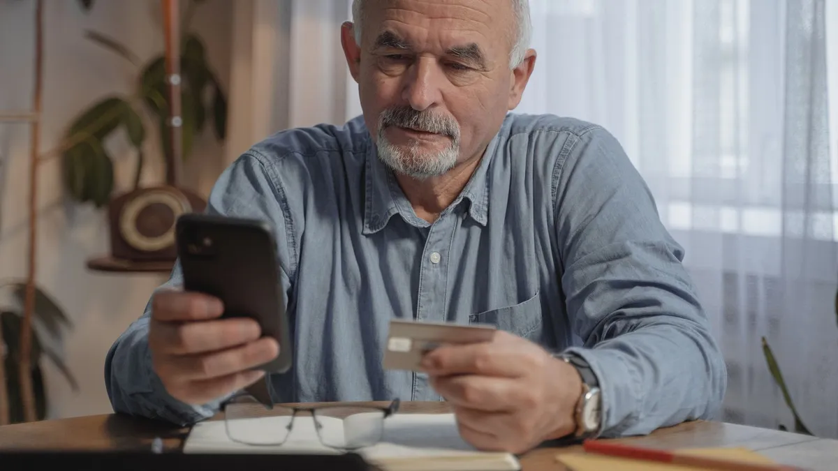 Retired man checking a pension deposit in his phone banking app before a loan payment